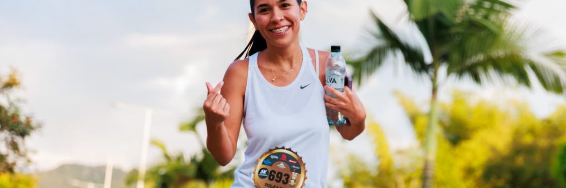 Smiling woman running a marathon outdoors in warm weather.